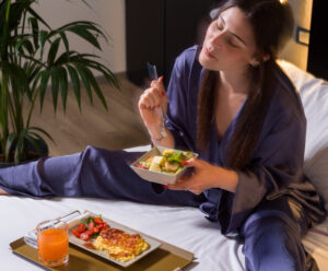 ragazza che fa colazione in camera a letto una hotels one catania siracusa